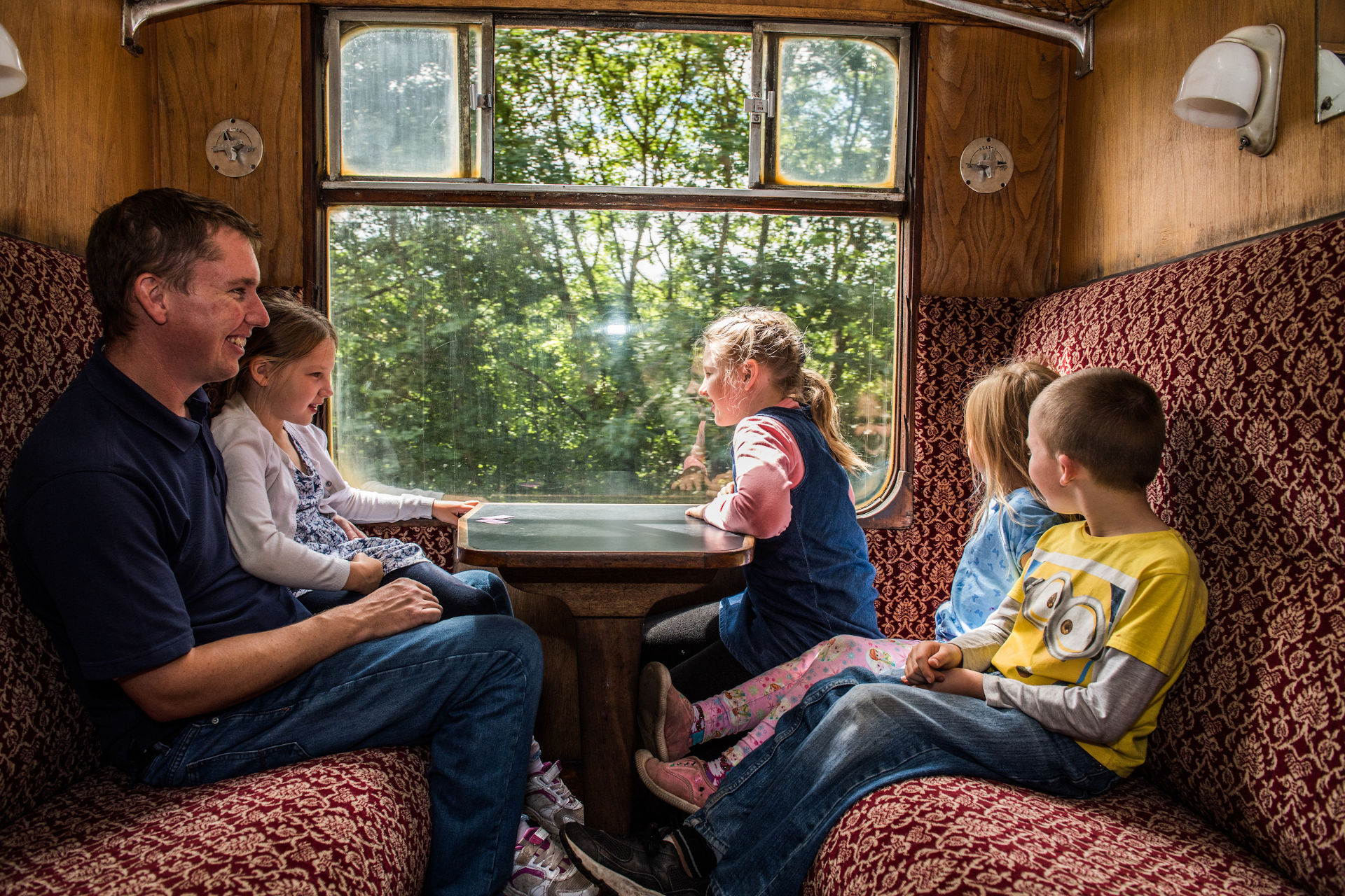 A happy family sit in a heritage train coach